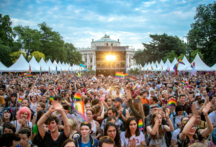 Menschenmenge mit Regenbogenflaggen und Zelten auf der Seite auf dem Vienna Pride.