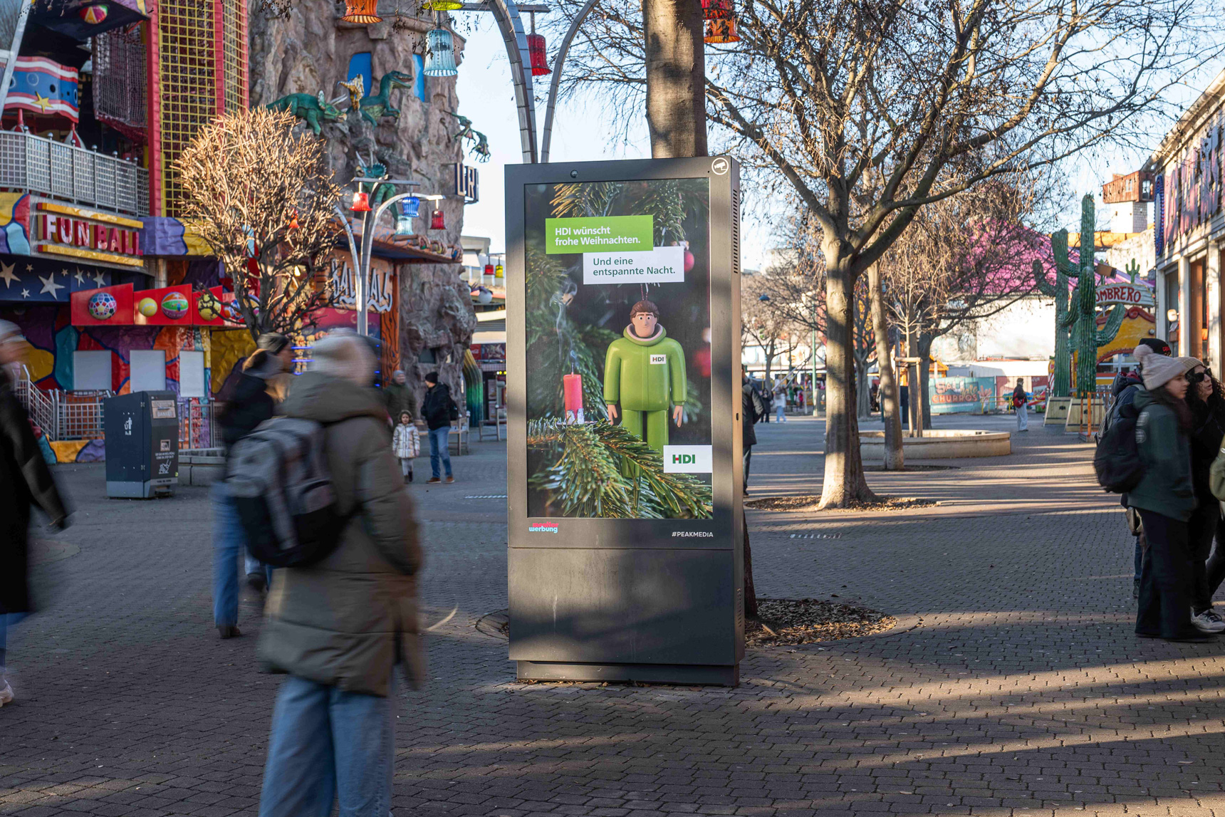 Eine Person steht vor einem Outdoor Bildschirm mit Werbung im Wiener Prater
