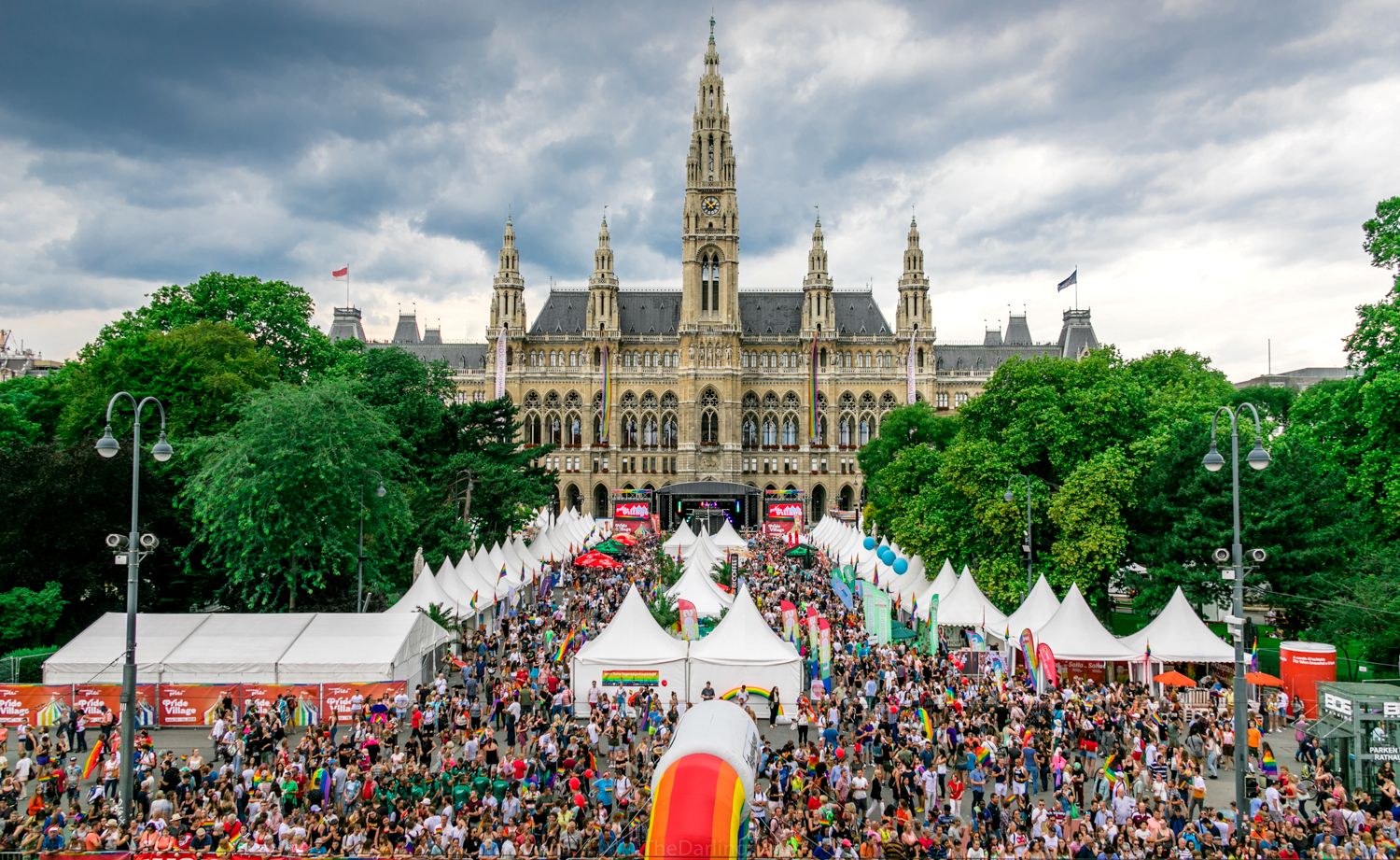 Vogelperspektive vom Event Vienna Pride. Menschenmenge von der Bühne. Zelte links und rechts. Und hinter der Bühne ist das Wiener Rathaus zusehen.
