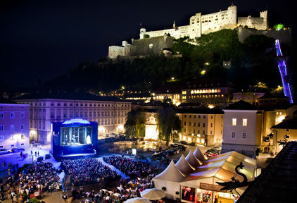 Festspielnächte Salzburg. Im Vordergrund eine große Videowall mit Publikum und im Hintergrund die Burg von Salzburg